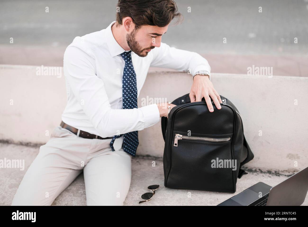 Giovane uomo che guarda dentro uno zaino nero Foto Stock