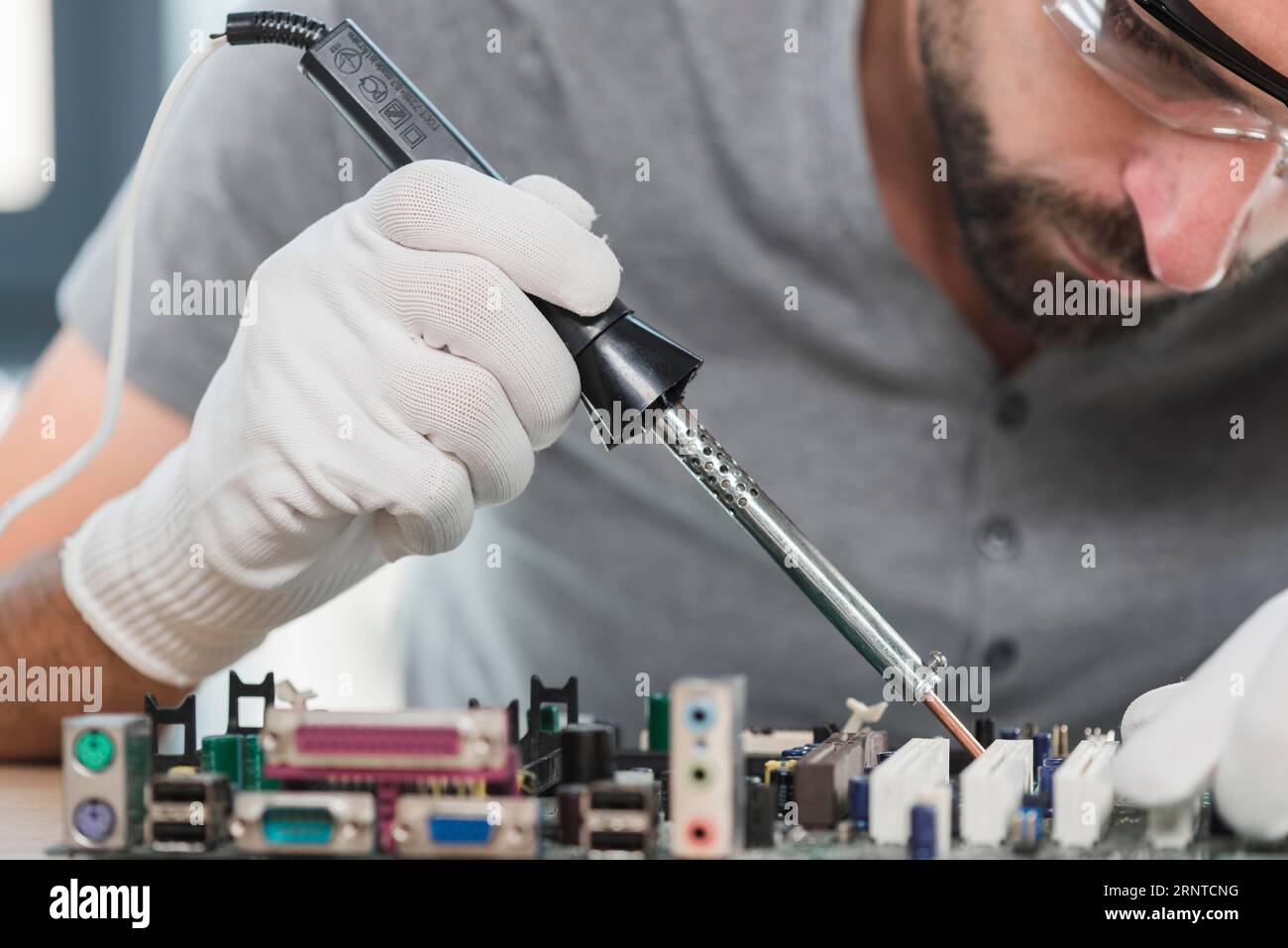 Officina di saldatura a distanza ravvicinata del circuito del computer per saldatura MAN Foto Stock