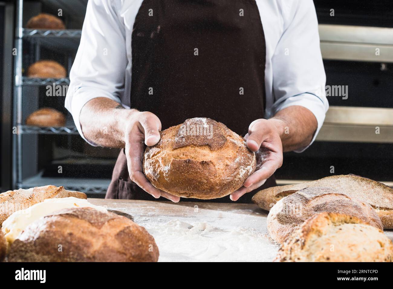 Primo piano del fornaio maschile che mostra pane a forma di pane Foto Stock