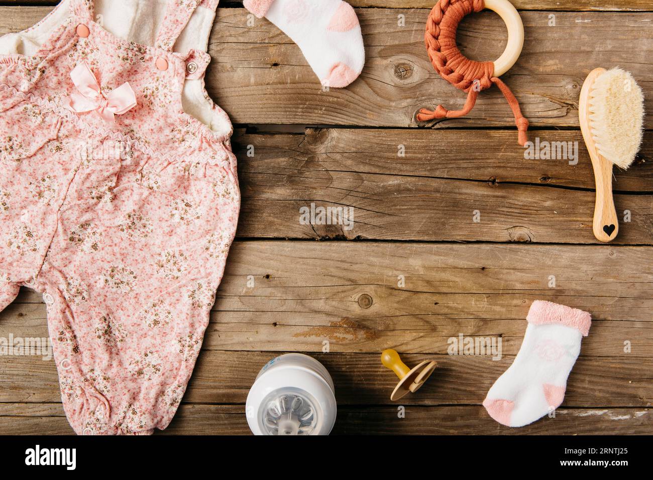 Baby s abito spazzola succhietto giocattolo calze latte biberon tavolo in legno Foto Stock