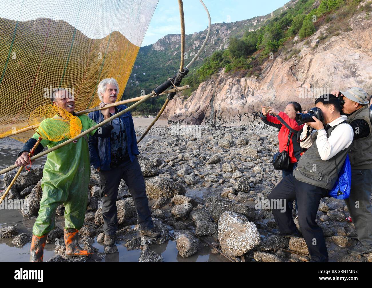 (171113) -- XIAPU, 13 novembre 2017 -- Jiang Lianshui (1st L) posa per fotografi al villaggio Beiqi della contea di Xiapu, provincia del Fujian della Cina sud-orientale, 9 novembre 2017. La contea di Xiapu, che vanta 480 km di costa e 69 333 ettari di pianura fangosa, è famosa per il suo pittoresco paesaggio di spiagge e attira gruppi di appassionati di fotografia per scattare foto. In questo modo aumenta la domanda di modelli in grado di mostrare la cattura del pesce in modo tradizionale. Il 67enne Jiang Lianshui è uno di quei nuovi modelli. Jiang cambiò la sua carriera da pescatore a lavorare come modello a tempo pieno nel 2007. Lui è soddisfatto Foto Stock