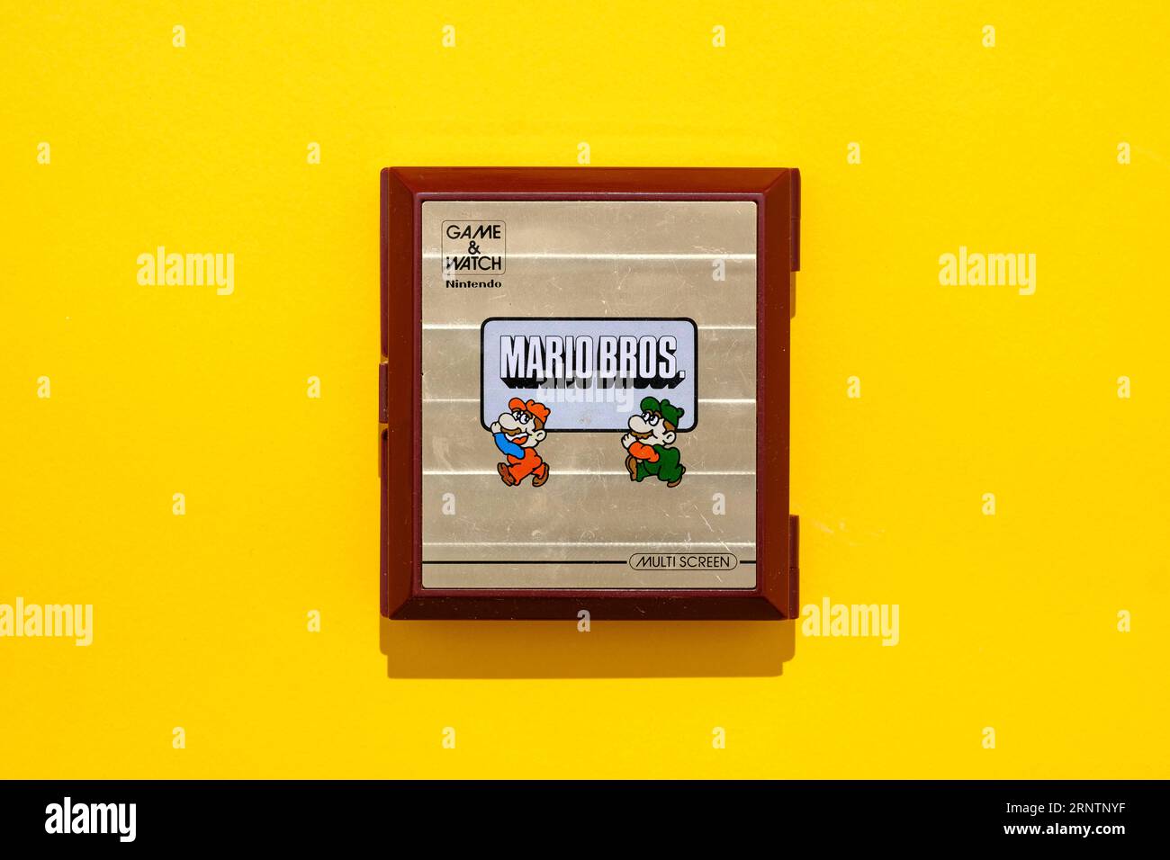 Originale portatile di Nintendo con Mario e Luigi, Mario Bros., con 2 display, vista dall'alto di fronte a sfondo giallo Foto Stock
