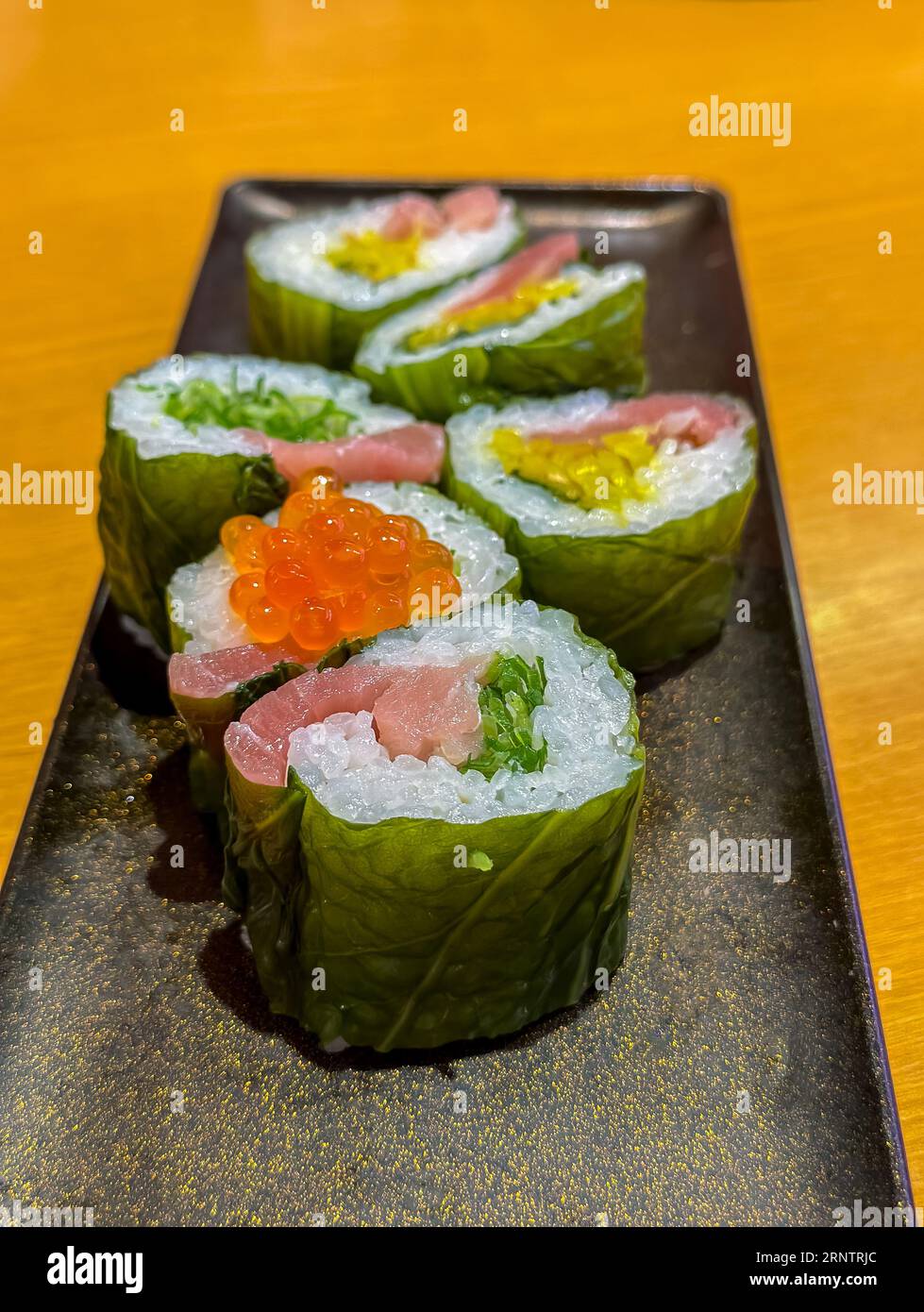 Panini sushi ripieni di pesce e verdure disposti su un piatto. Foto Stock