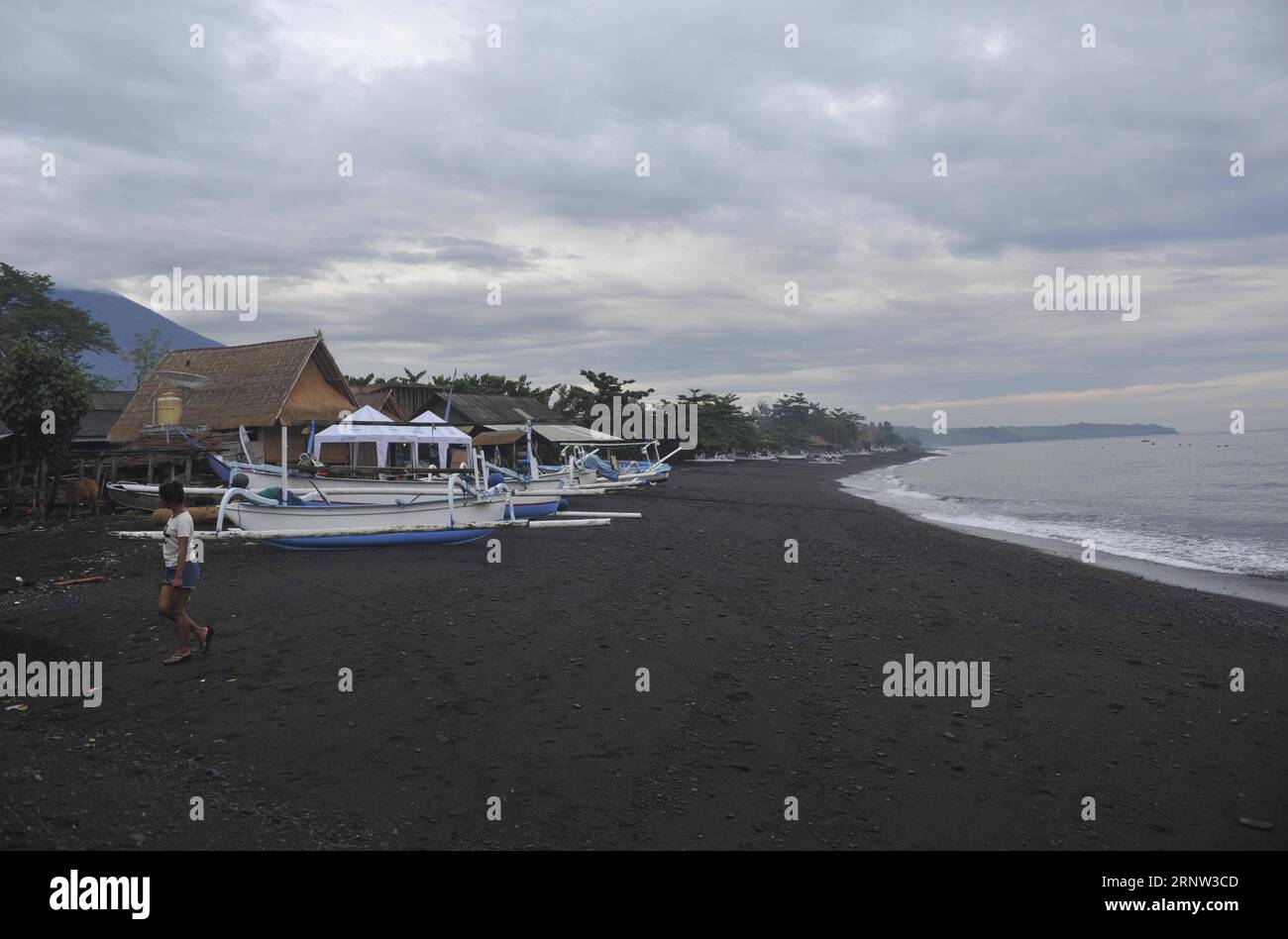 (171202) -- BALI, 2 dicembre 2017 -- Una donna locale cammina sulla spiaggia di Amed a Karangasem, Bali, Indonesia, 2 dicembre. 2017. Gli impatti derivanti dalle crescenti attività vulcaniche del Monte Agung, nell'isola indonesiana di Bali, hanno colpito direttamente coloro che si guadagnano da vivere con attività turistiche ad Amed, un'area costiera orientale di Bali ben nota per le sue bellissime spiagge, il surf e i punti di immersione. Zulkarnai) (gj) INDONESIA-BALI-MONTE AGUNG-IL TURISMO IMPATTI *Zulkarnain* PUBLICATIONxNOTxINxCHN Foto Stock