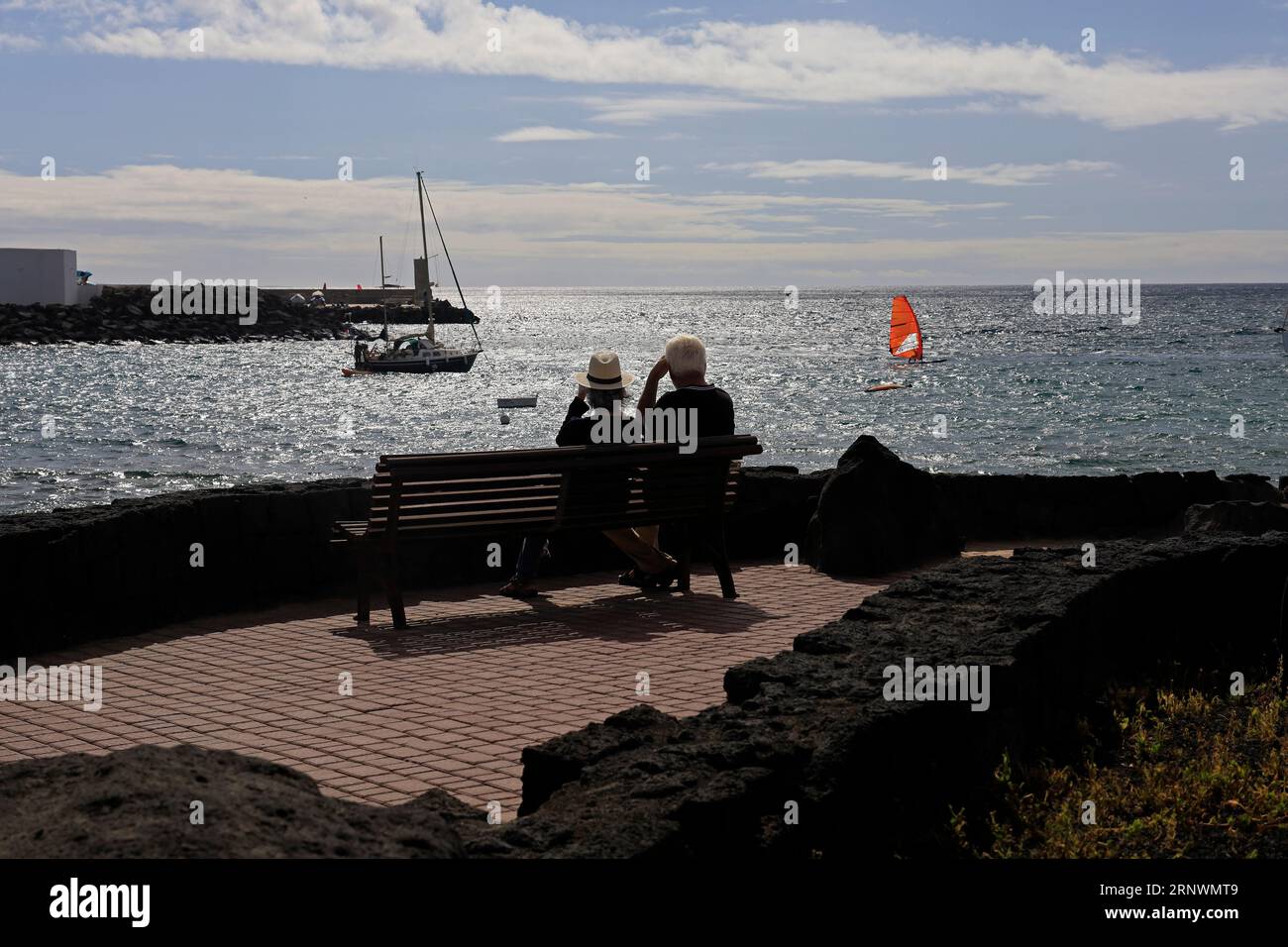 Coppia matura seduta su una panchina che si affaccia sul mare a Playa Blanca, Lanzarote, Isole Canarie, Spagna Foto Stock