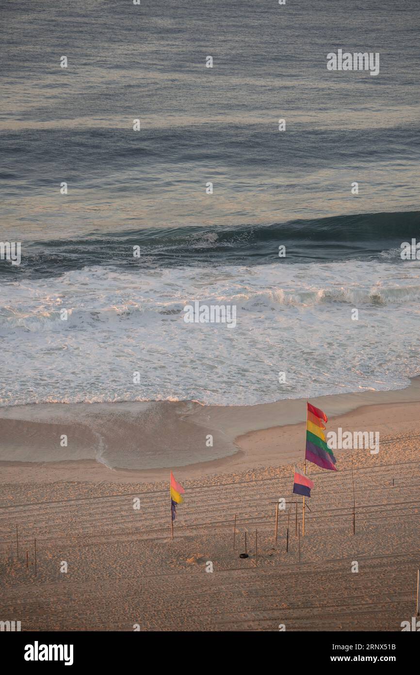Rio de Janeiro, Brasile: Al mattino presto e bandiere arcobaleno su una spiaggia desertica di Copacabana, una delle famose spiagge della città Foto Stock