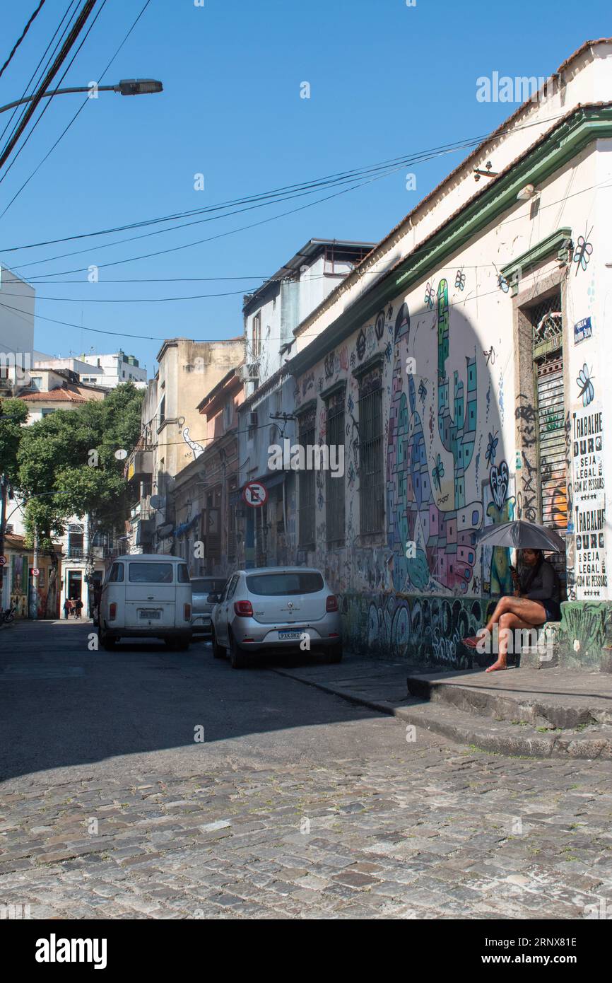 Rio de Janeiro: Ragazza con un ombrello per ripararsi dal sole nel quartiere di Lapa, famoso per i monumenti storici, l'architettura coloniale e la vita notturna Foto Stock