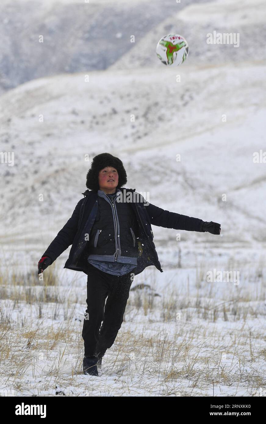 (180203) -- ILI, 3 febbraio 2018 -- Yeyeni, 14, gioca a calcio sul pascolo nella valle di Akyaz, nella contea di Zhaosu, nella regione autonoma di Xinjiang Uygur della Cina nord-occidentale, 16 gennaio 2018. Trascorrerà le vacanze invernali con i suoi genitori nella valle. A circa 130 chilometri dalla città più vicina, la valle di Akyaz è un importante luogo di pascolo invernale per i pastori della contea di Zhaosu, nello Xinjiang. Nonostante un'altitudine di 2.000 metri, la valle di Akyaz ha un clima più caldo rispetto alle aree circostanti e abbondante erba e acqua. A volte viene definita la valle della vita. Per secoli, l'allevamento è stato un tr ancestrale Foto Stock