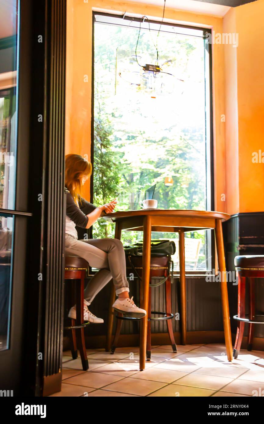 Giovane donna che lavora su un computer portatile al Park Ave Cafe nel quartiere South Park Blocks nel centro di Portland, Oregon Foto Stock