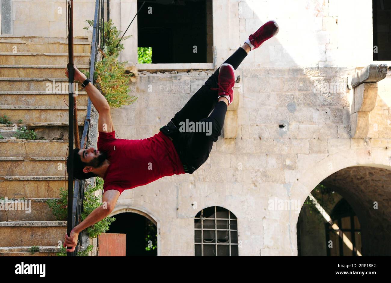 (180617) -- ALEPPO, 17 giugno 2018 -- Un giovane giocatore di parkour siriano esegue la mossa della bandiera umana in una casa abbandonata nella parte in gran parte danneggiata della città di Aleppo, nella Siria settentrionale, l'8 giugno 2018. Con le loro acrobazie mozzafiato e salti acrobatici, un gruppo di giovani siriani sta riportando vita nelle parti distrutte della città di Aleppo con la loro elettrizzante esibizione in Parkour. PER ANDARE CON la caratteristica: I giovani siriani rianimano la vita nelle vecchie rovine di Aleppo con un'elettrizzante prestazione di Parkour. ) (hy) SYRIA-ALEPPO-PARKOUR-FEATURE AmmarxSafarjalani PUBLICATIONxNOTxINxCHN Foto Stock