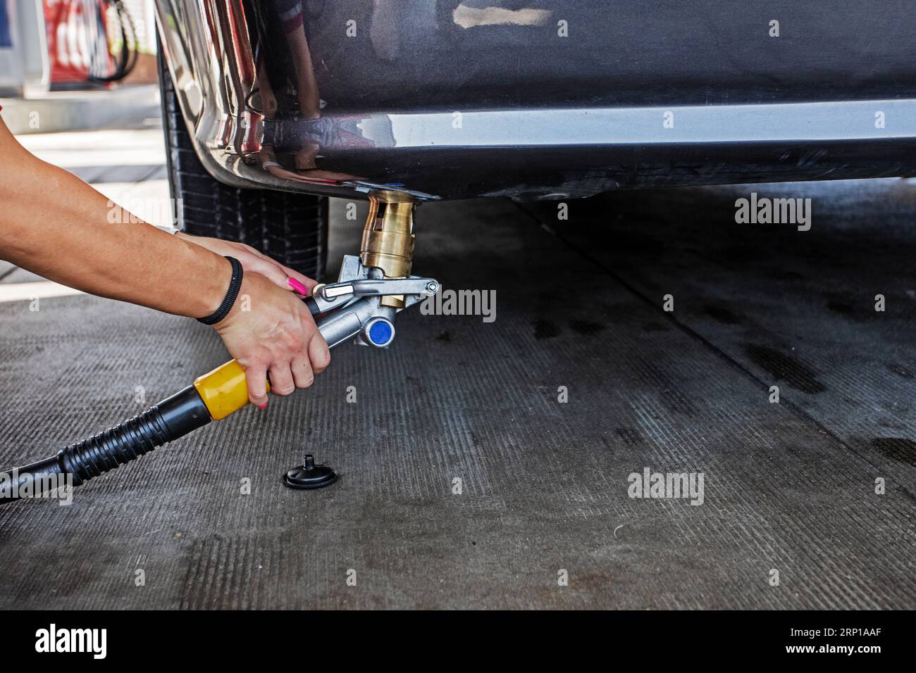Il personale femminile con le mani ben curate rifornisce una pistola a gas in un'auto da un cliente GPL. L'economia e la crisi mondiale Foto Stock