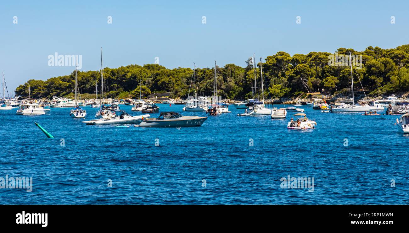 Cannes, Francia - 31 luglio 2022: Panorama dell'isola di Ile Saint Honorat con costa forestale e yacht sulle acque del Mar Mediterraneo al largo di Cannes, sulla Riviera Foto Stock