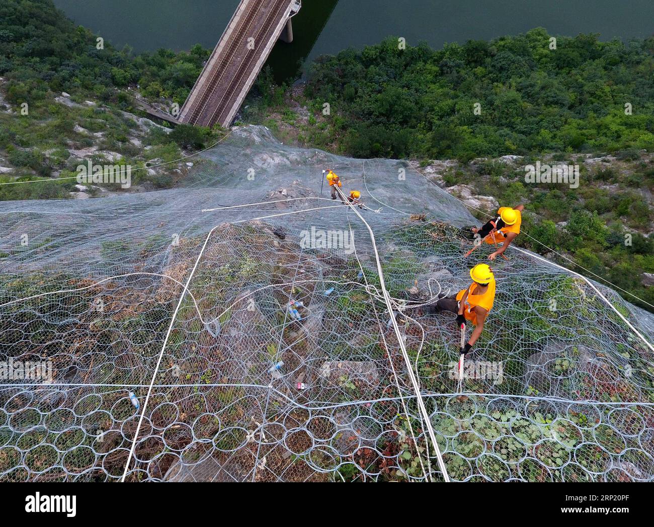 (180809) -- ZHENGZHOU, 9 agosto 2018 -- i membri del personale scalano una scogliera per eliminare potenziali rocce che cadono sopra un tunnel della ferrovia Houma-Yueshan nella provincia centrale di Henan, 9 agosto 2018. Gli addetti alla manutenzione ferroviaria lavorano sulla scogliera per liberare rocce sciolte sopra un tunnel ferroviario durante la stagione delle alluvioni. (Zyd) CHINA-HENAN-RAILWAY SAFETY (CN) LixJianan PUBLICATIONxNOTxINxCHN Foto Stock