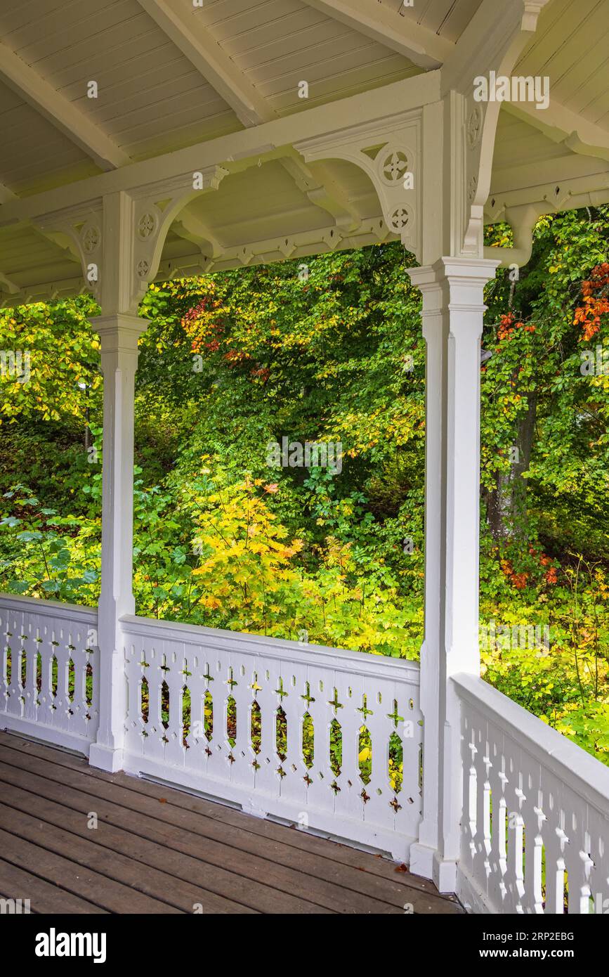 Veranda in legno con pavimento in legno e una ringhiera bianca e splendidi colori autunnali, Svezia Foto Stock
