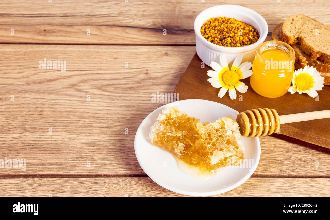 Fetta di pane al miele con polline d'api a nido d'ape con superficie in legno Foto Stock