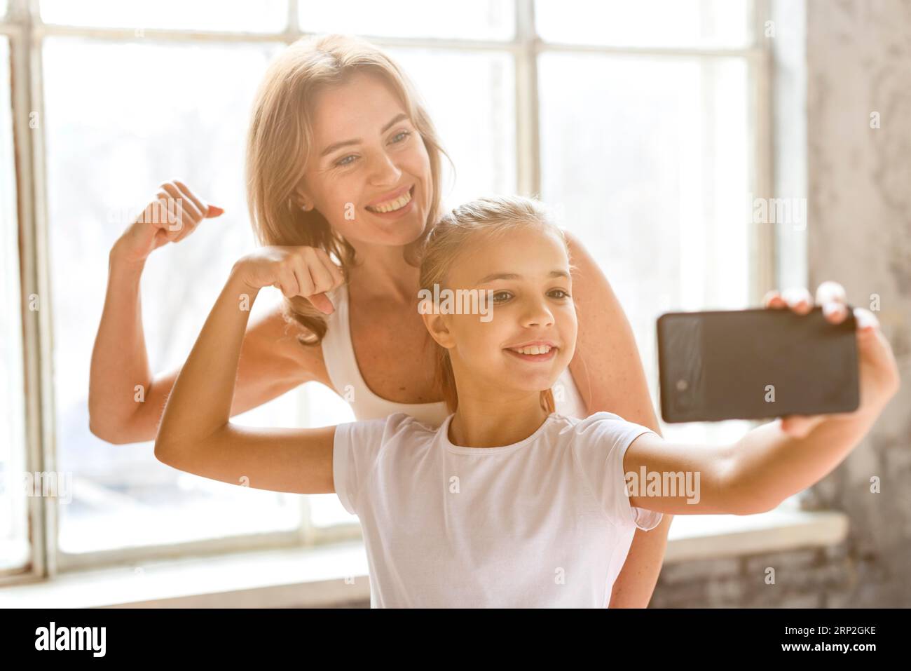 Madre figlia che prende selfie flexing muscoli del braccio Foto Stock