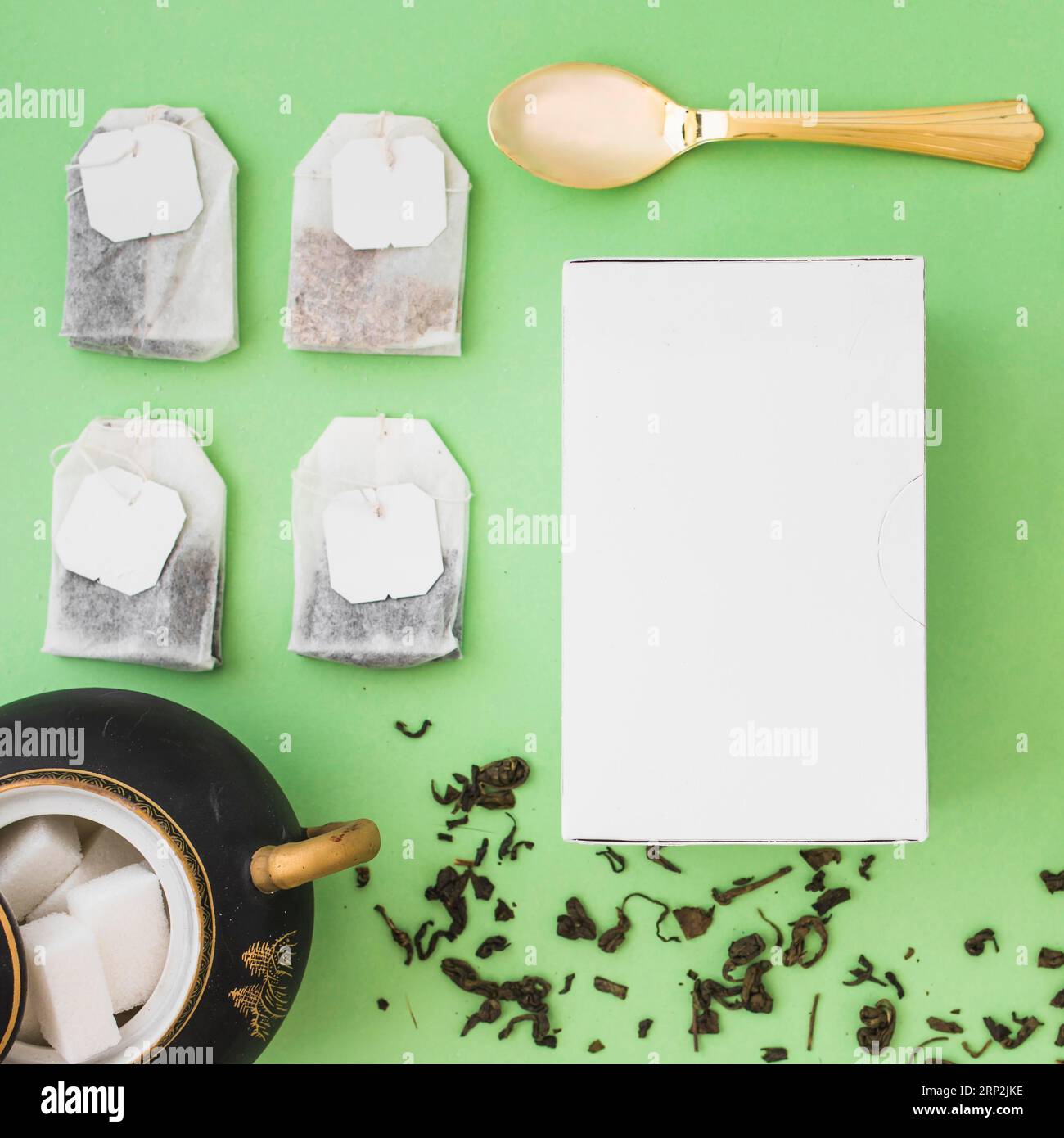 Diversi tipi di bustine di tè alle erbe zucchero cubetti cucchiaio bianco scatola fondo colorato Foto Stock