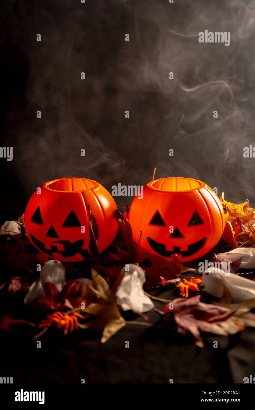 Zucche di Halloween su foglie autunnali con fumo su sfondo nero, copia spazio per incollare Foto Stock