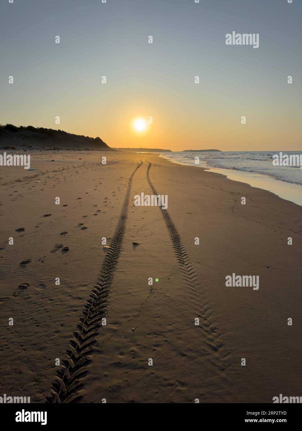 Binari pneumatici sulla spiaggia. Tramonto sulla lunga e vuota spiaggia. Verticale Foto Stock