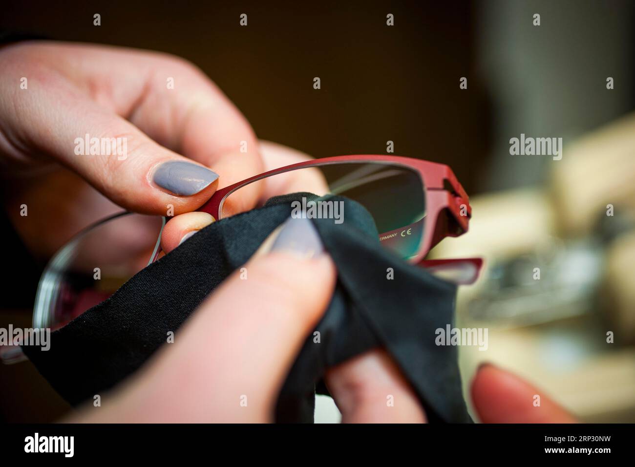 Una donna pulisce un paio di occhiali e lenti da vista Foto Stock
