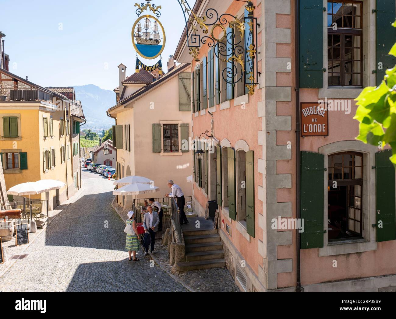 Cameriere e clienti chiacchierano fuori dalla Brasserie Auberge de l'onde, Saint Saphorin, nella regione vinicola di Lavaux, Cantone di Vaud, Svizzera. Foto Stock