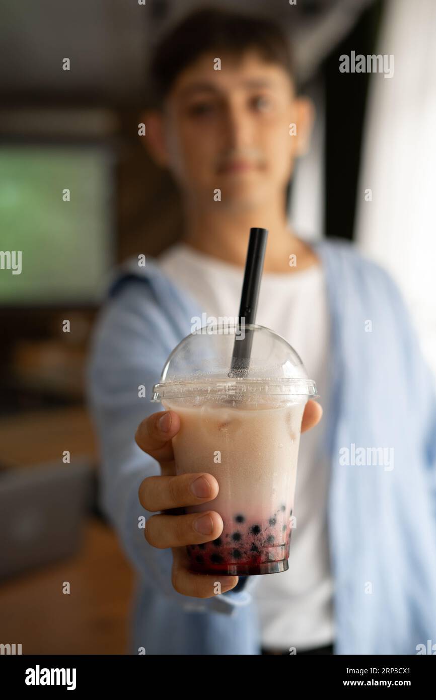 Uomo che tiene in mano il tè bollicine di latte ghiacciato con perle di tapioca e lo mostra alla macchina fotografica, bevanda tradizionale di Taiwan. Foto Stock