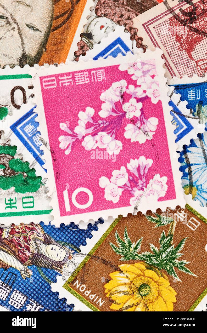 Madrid, Spagna; 08-13-2023: Francobollo dal Giappone con fiori di ciliegio su sfondo rosa con più francobolli che formano uno sfondo Foto Stock