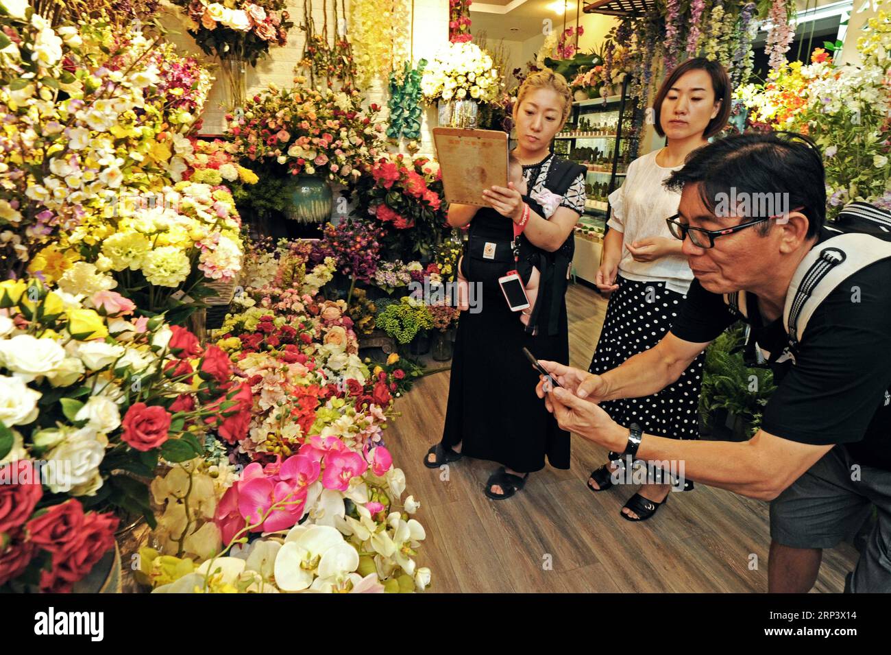 (181018) -- HANGZHOU, 18 ottobre 2018 (Xinhua) -- Un uomo d'affari giapponese scatta foto di fiori simulati in un negozio all'interno della Yiwu International Trade City a Yiwu, nella provincia dello Zhejiang, nella Cina orientale, il 10 settembre 2018. Nei primi tre trimestri del 2018, il valore totale delle importazioni e delle esportazioni di Zhejiang ha raggiunto 2,11 trilioni di yuan (304,64 miliardi di dollari USA), crescendo del 12,5% su base annua, con un incremento delle esportazioni del 9,7%, raggiungendo 1,57 trilioni di yuan (226,67 miliardi di dollari), e l'importazione è aumentata del 21,4%, raggiungendo rispettivamente 544,72 miliardi di yuan (78,64 miliardi di dollari) anno dopo anno. (Xinhua/Tan Jin) (sxk Foto Stock