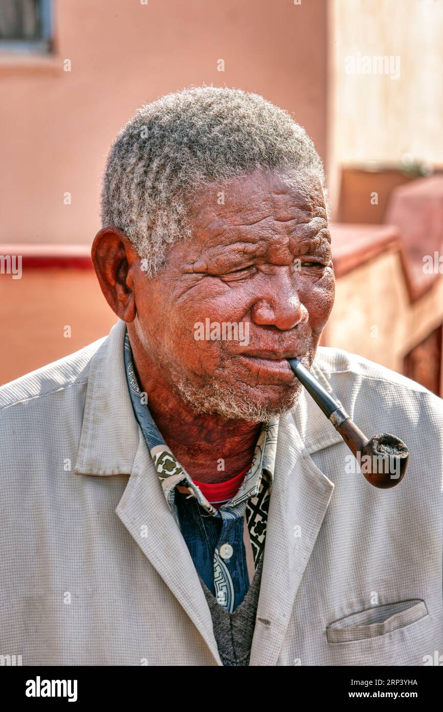 vecchio in un villaggio africano con i denti cattivi che fumano pipa tradizionale Foto Stock
