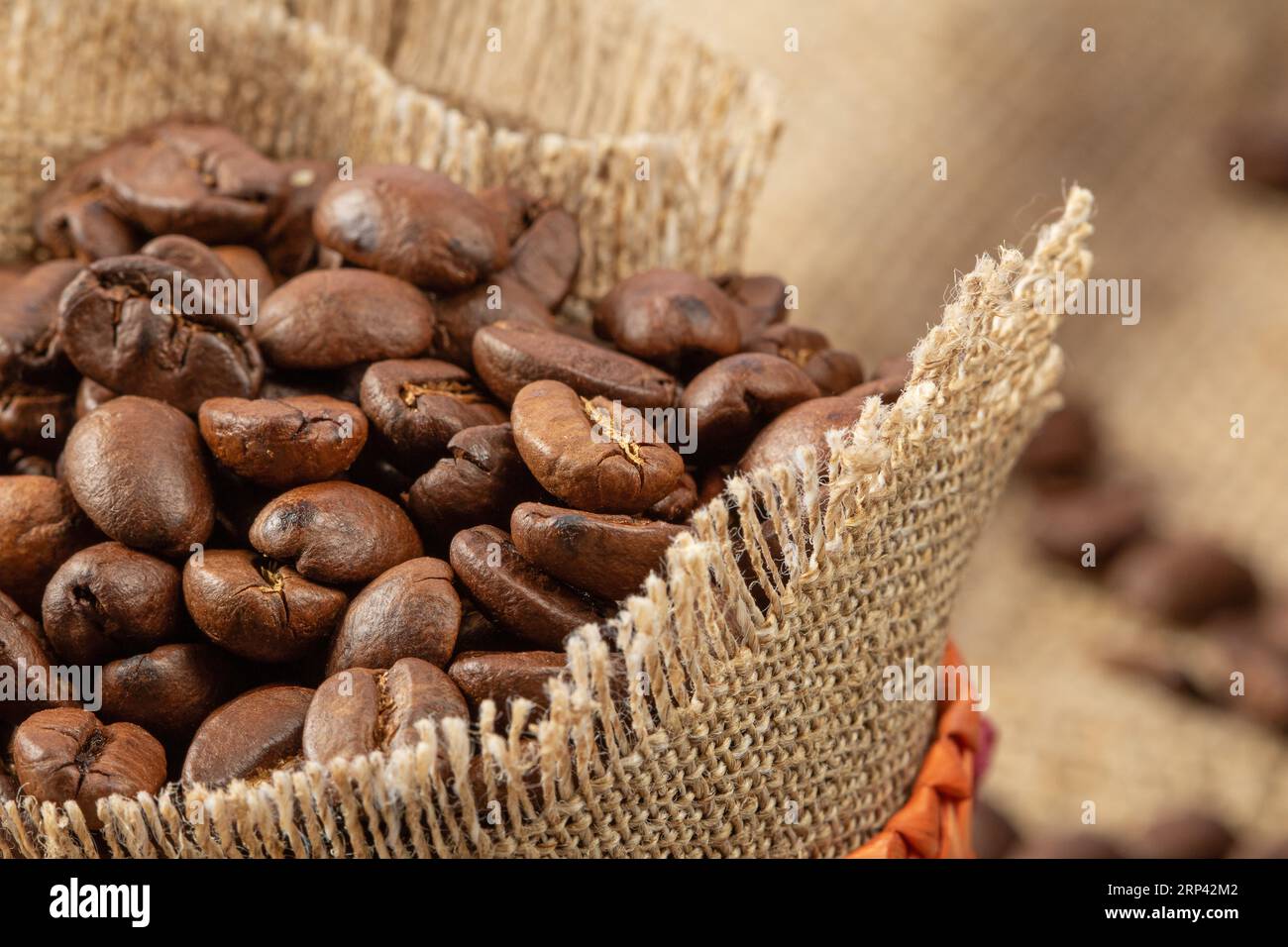 Borsa in juta con chicchi di caffè su uno sfondo di burlap, primo piano, stile rustico. Foto Stock