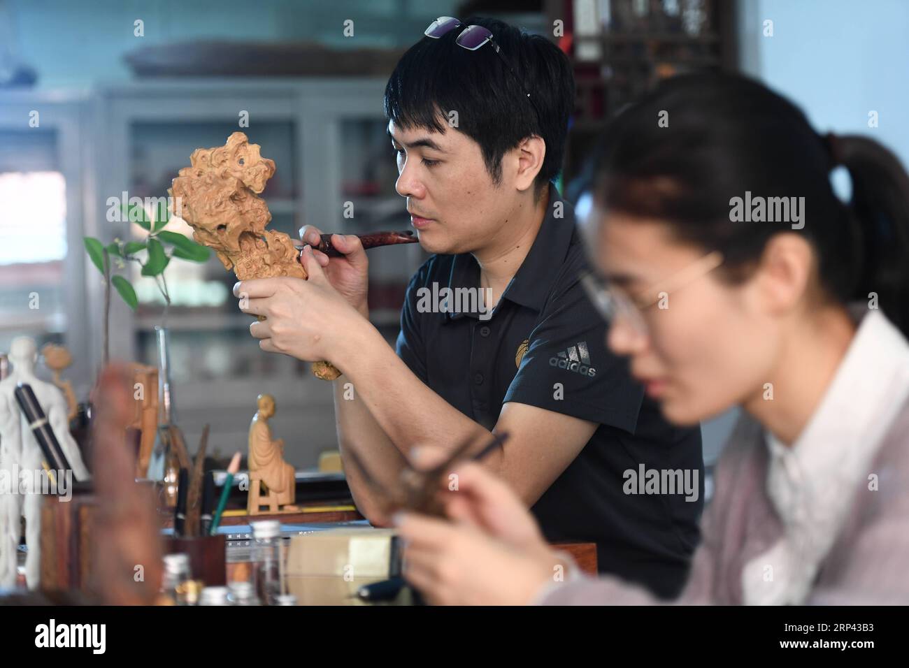 (181024) -- PUTIAN, 24 ottobre 2018 -- Lin Jianjun (L) e Chen Qin realizzano sculture in legno nel loro studio a Putian, nella provincia del Fujian della Cina sudorientale, 24 ottobre 2018. LIN Jianjun, che ha imparato l'intaglio del legno all'età di 16 anni, ha studiato l'abilità di fare questa opera d'arte tradizionale per più di 20 anni. Nel 2014, Lin si sposò con Chen Qin. La moglie fu influenzata dal marito e si interessò all'intaglio del legno. Sviluppò l'intaglio del legno combinando un'abilità tradizionale per fare intaglio del legno intarsiato con oro e argento. La coppia nel frattempo cerca di promuovere l'intaglio del legno di Putian dando meno Foto Stock