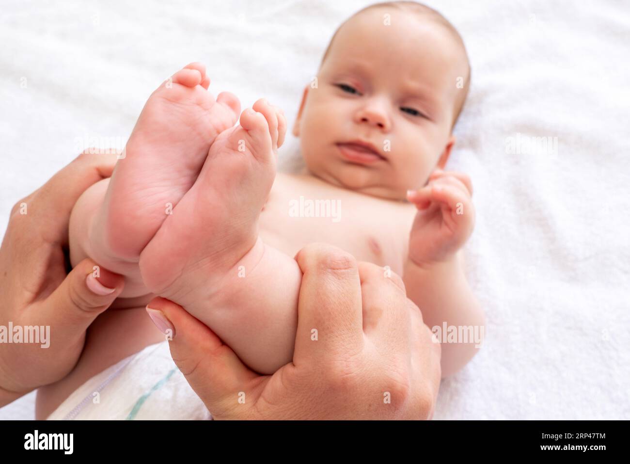 Il tocco delicato della mamma sulle gambe del bambino. Concetto di alleviare la costipazione e le coliche infantili Foto Stock