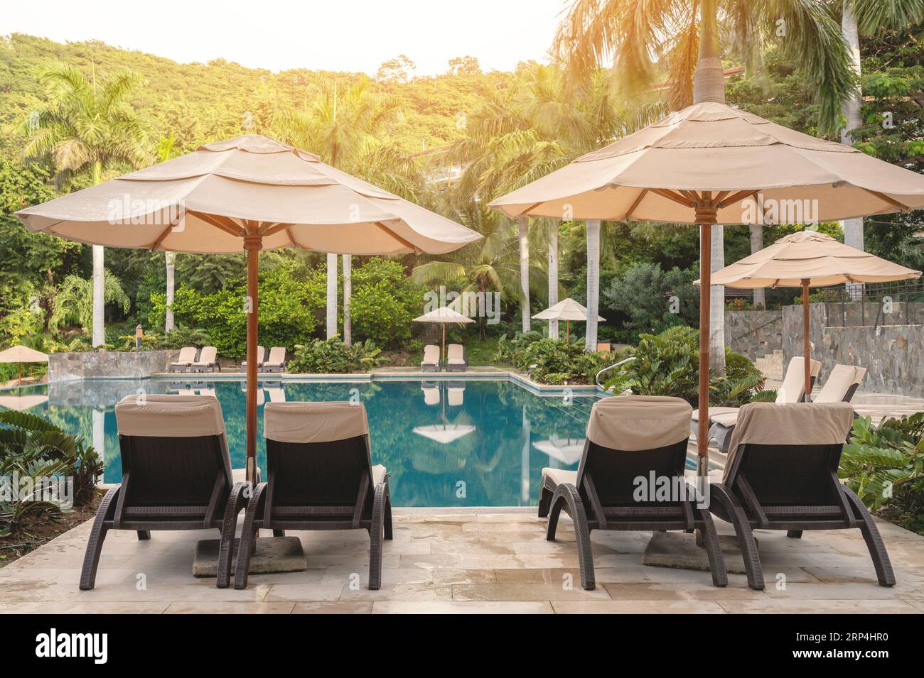 Vacanze in paradiso tropicale. Sedie a sdraio e ombrellone accanto alla piscina Foto Stock