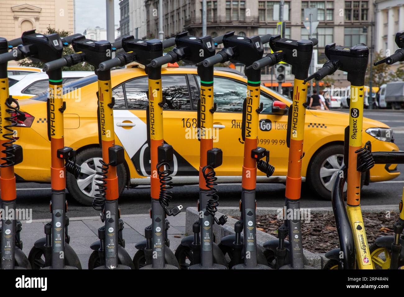 Mosca, Russia. 3 settembre 2023. Scooter elettrici in un punto stradale del servizio di noleggio scooter Whoosh sullo sfondo di un taxi Yandex nel centro di Mosca, in Russia Foto Stock