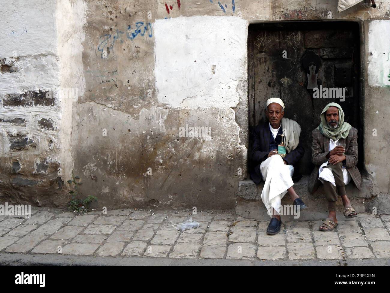 181119 -- SANAA, 19 novembre 2018 -- uomini yemeniti siedono alla porta di una casa a Sanaa, Yemen, 19 novembre 2018. Domenica sera i ribelli Houthi dello Yemen hanno annunciato la sospensione dell'attacco missilistico contro l'Arabia Saudita e gli Emirati Arabi Uniti. dhf YEMEN-SANAA-DAILY LIFE-HOUTHI-OPERAZIONE MILITARE-STOP MohammedxMohammed PUBLICATIONxNOTxINxCHN Foto Stock