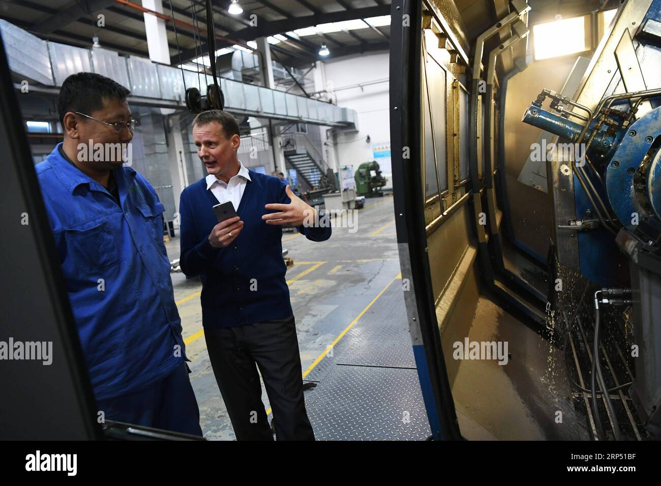 (181123) -- LANZHOU, 23 novembre 2018 -- Stephan Mueller parla con il suo collega nella loro fabbrica a Lanzhou, capitale della provincia del Gansu della Cina nord-occidentale, 23 ottobre 2018. Stephan, 48 anni, venne in Cina per lavorare come espatriato dalla Germania nel 2006, e 4 anni dopo aveva una propria casa in Cina dopo aver sposato una moglie cinese. Negli anni successivi, viaggiò molto in Cina con sua moglie, fece più amici e imparò di più sulla società cinese. ) (clq) CHINA-LANZHOU-FOREIGNER-LIFE (CN) ChenxBin PUBLICATIONxNOTxINxCHN Foto Stock