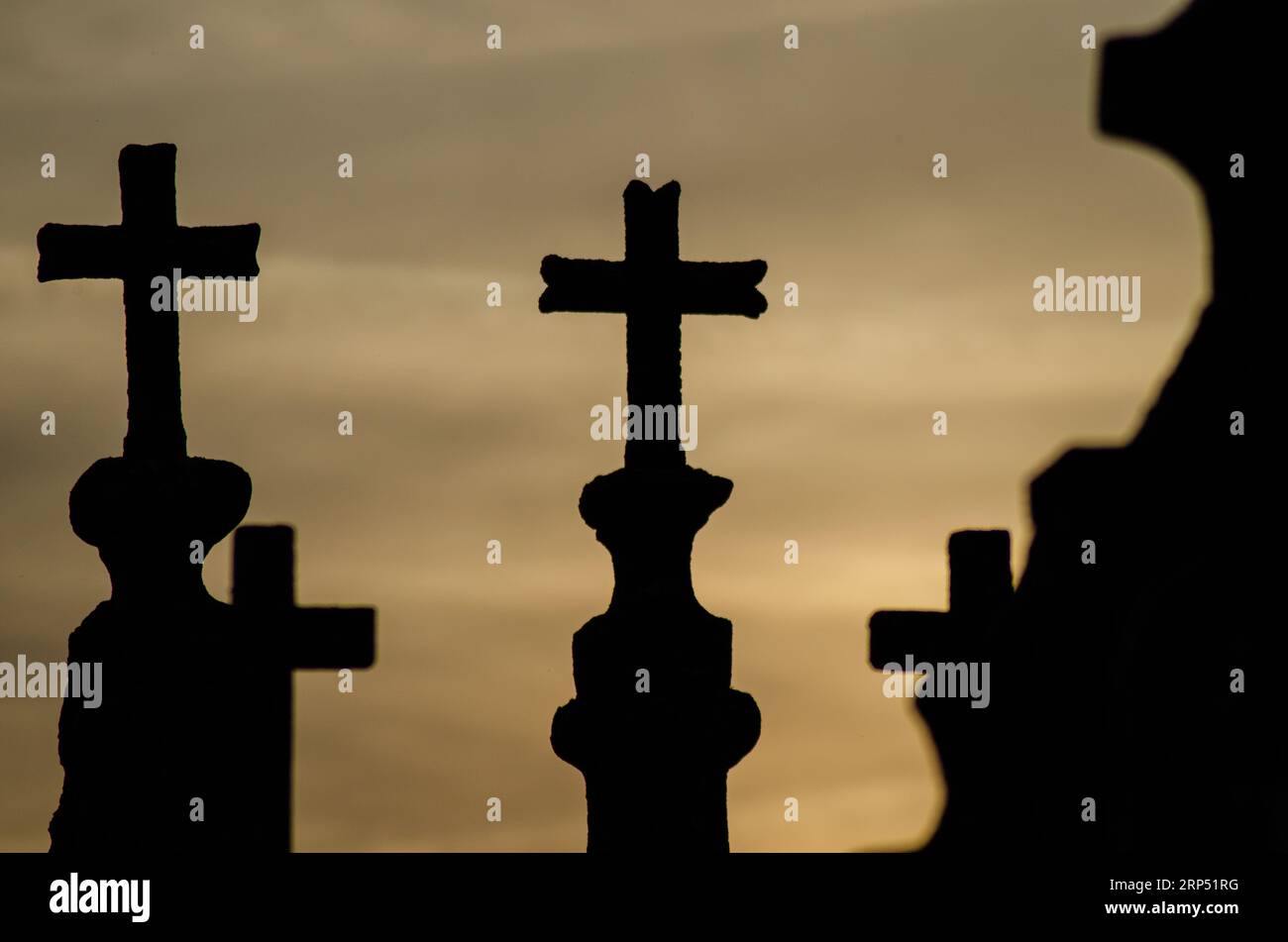 Silhouette di croci funerarie in un cimitero cristiano al tramonto. Foto Stock