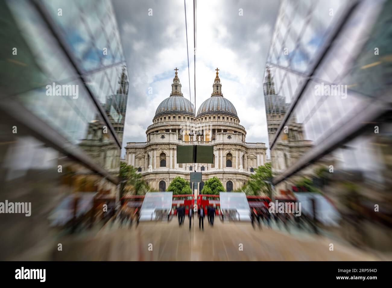 Cattedrale di St Paul riflessa in moderni edifici in vetro, con autobus rossi di Londra e gente che passeggia. Concentrati sulla cattedrale con sfocatura zoom. Foto Stock