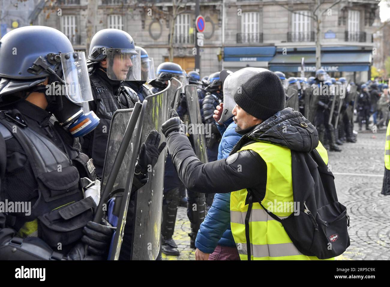 (181208) -- PARIGI, 8 dicembre 2018 -- Un manifestante si confronta con la polizia vicino all'Arco di Trionfo a Parigi, in Francia, l'8 dicembre 2018. La polizia antisommossa ha sparato gas lacrimogeni e cannoni ad acqua ai manifestanti Yellow Vests che marciano a Parigi sabato nel quarto week-end, nonostante la serie di concessioni del presidente Emmanuel Macron. ) (yy) FRANCIA-PARIGI- GILET GIALLI -PROTESTA ChenxYichen PUBLICATIONxNOTxINxCHN Foto Stock