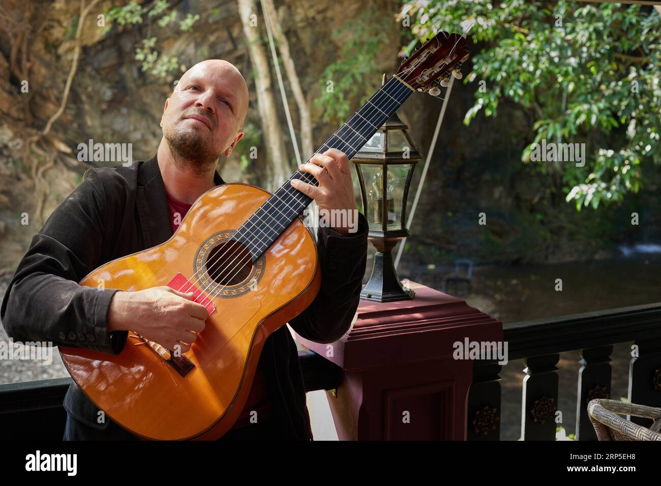 Uomo che suona la chitarra con espressione in mezzo alla bellezza della natura Foto Stock