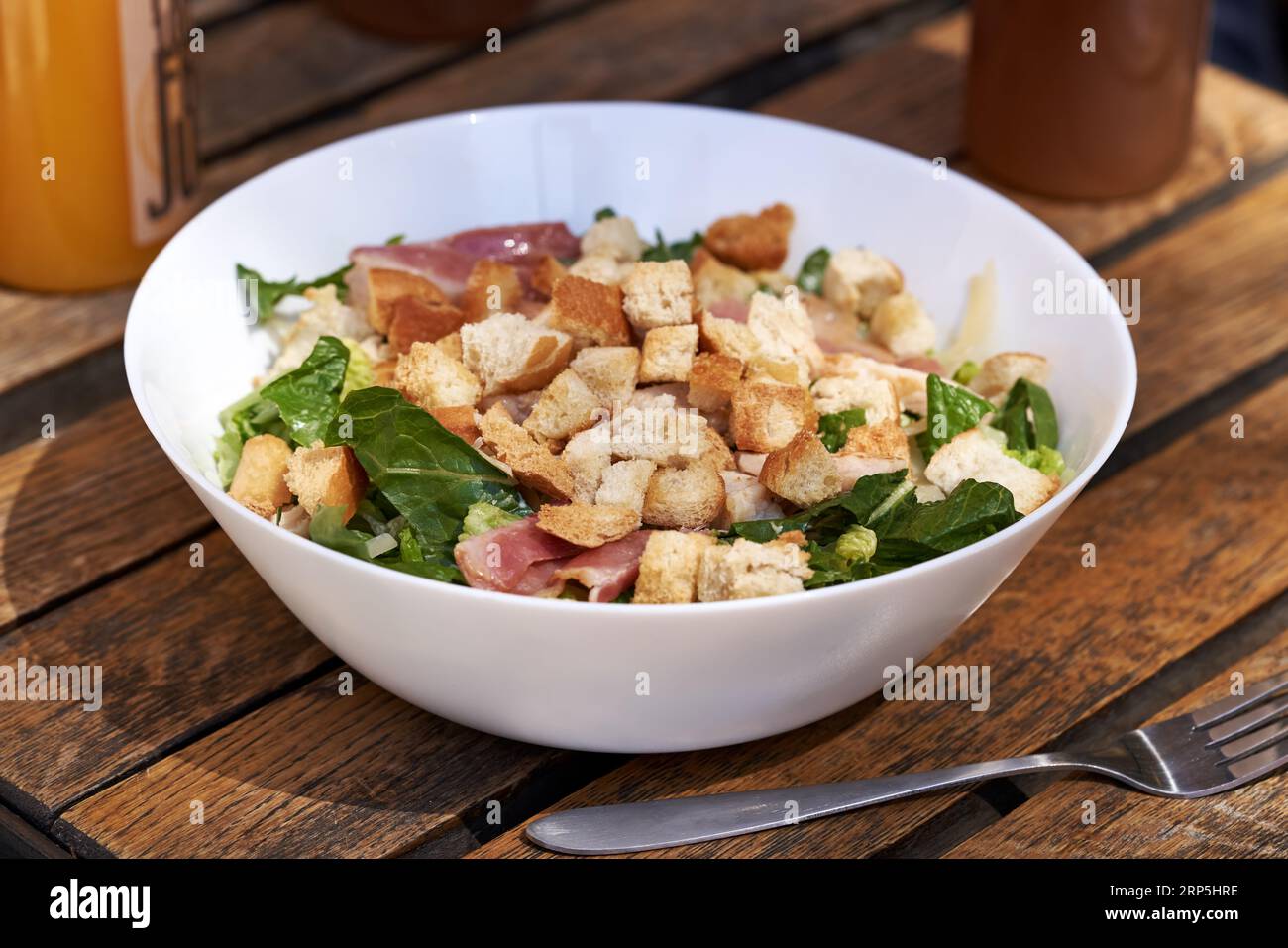 Insalata Caesar con lattuga, crostini, pancetta e pollo in un recipiente bianco Foto Stock