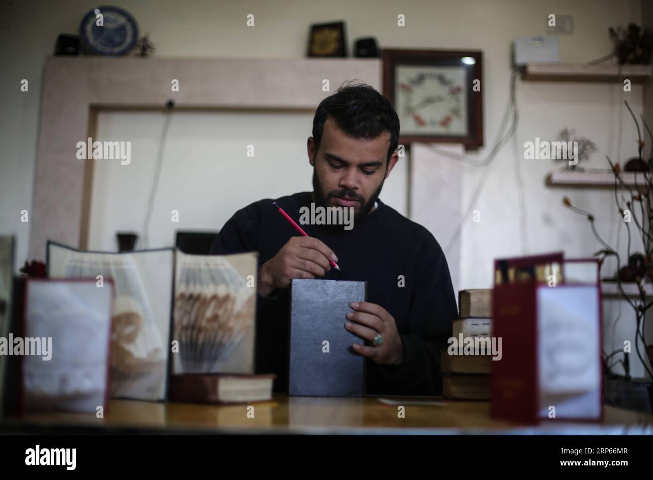 (190103) -- GAZA, 3 gennaio 2019 -- Ahmed Humaid, 28, piega fogli di carta per creare forme e parole all'interno della sua casa nel campo profughi di Nusseirat nella Striscia di Gaza centrale, il 31 dicembre 2018. Un giovane palestinese disoccupato proveniente da un campo profughi nella Striscia di Gaza trova un modo creativo per combattere la disoccupazione imparando l'Origami, o l'arte della piegatura della carta, online. Stringer) PER ANDARE CON la caratteristica: Gaza giovane padroneggia l'arte della piegatura della carta per combattere la disoccupazione MIDEAST-GAZA-CARTA FOLDING-ART MohammedxDahman PUBLICATIONxNOTxINxCHN Foto Stock