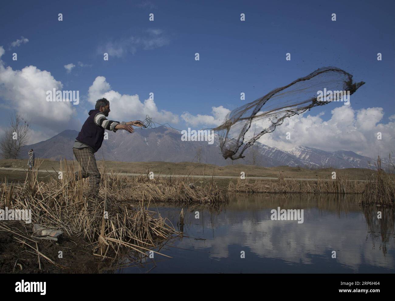 (190113) -- SRINAGAR, 13 gennaio 2019 (Xinhua) -- Un pescatore getta una rete in uno stagno in una giornata di sole nella città di Srinagar, la capitale estiva del Kashmir controllato dagli indiani, 13 gennaio 2019. La domenica il Kashmir controllato dagli indiani è stato testimone di una giornata di sole dopo tre giorni di pioggia e neve. (Xinhua/Javed Dar) KASHMIR-SRINAGAR-DAILY LIFE PUBLICATIONxNOTxINxCHN Foto Stock