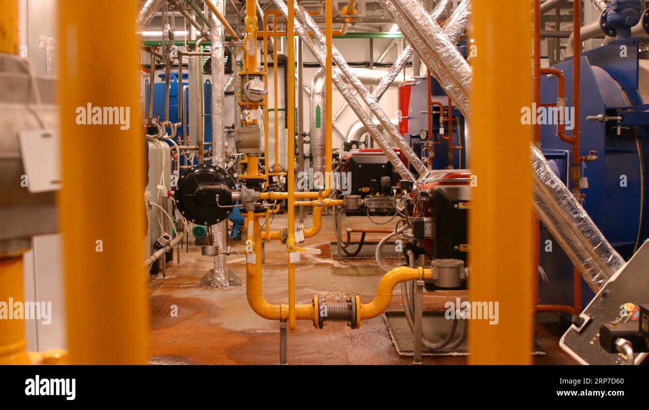 Tubi di riscaldamento e caldaie all'interno del locale caldaie Foto Stock