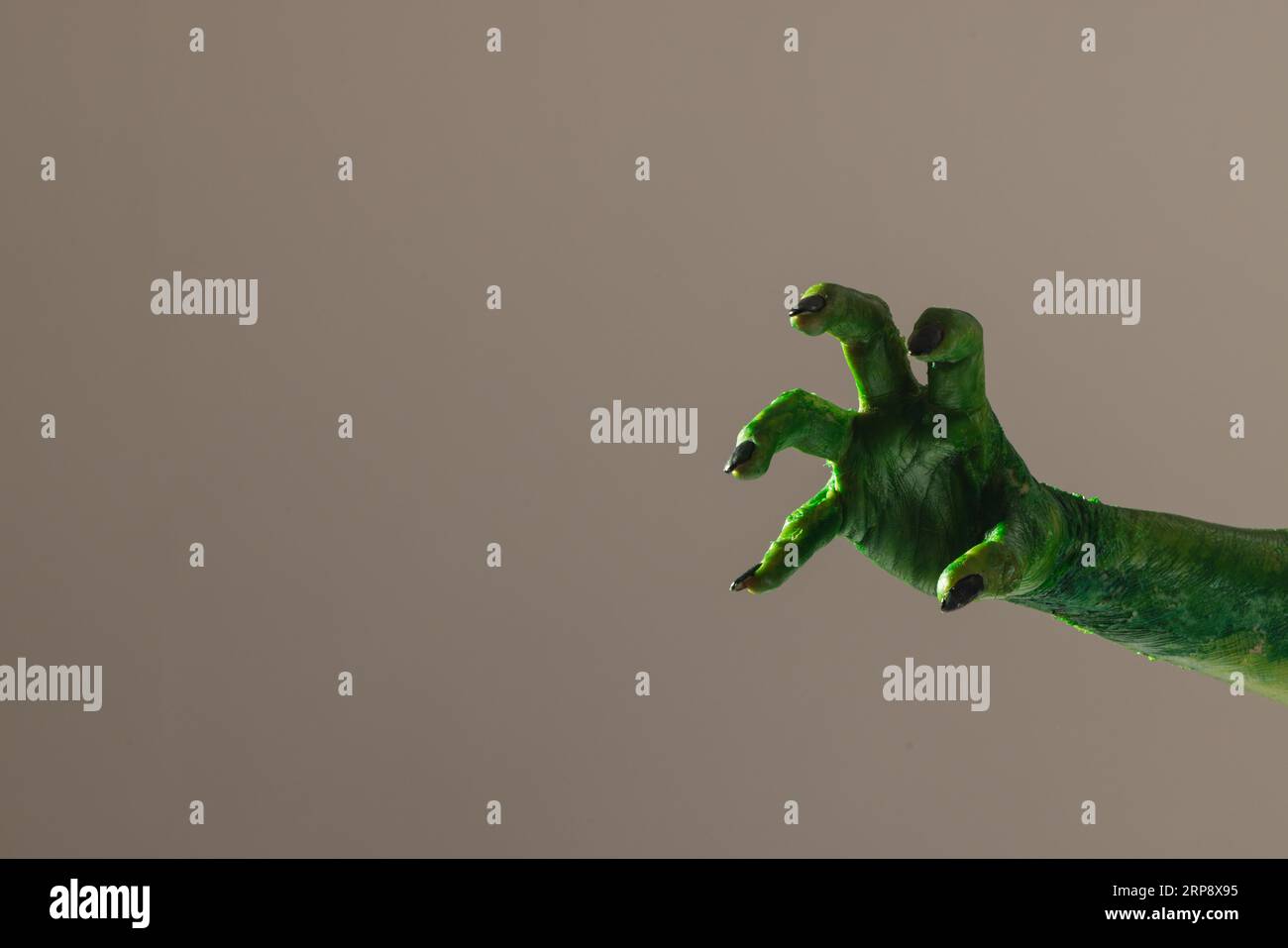 Mano mostro verde con unghie nere che raggiungono lo sfondo grigio Foto Stock