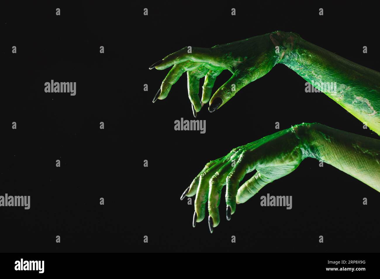 Lancette di mostro verde con unghie nere che raggiungono lo sfondo nero Foto Stock