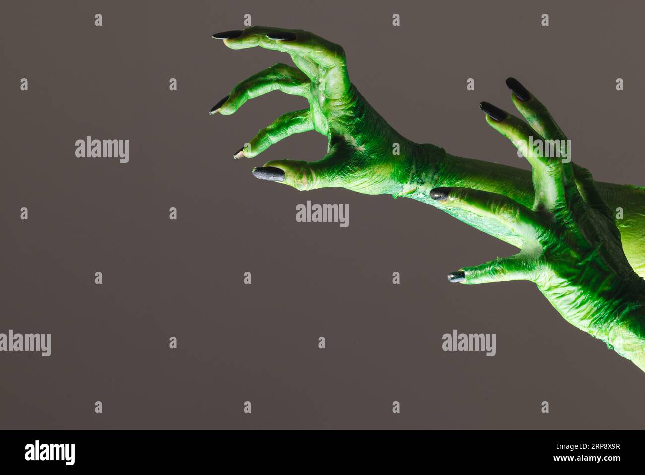 Lancette di mostri verdi con unghie nere su sfondo grigio Foto Stock