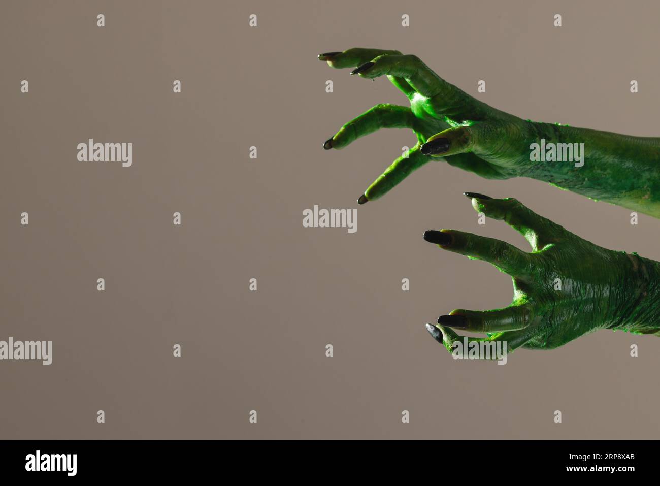 Lancette di mostri verdi con unghie nere su sfondo grigio Foto Stock