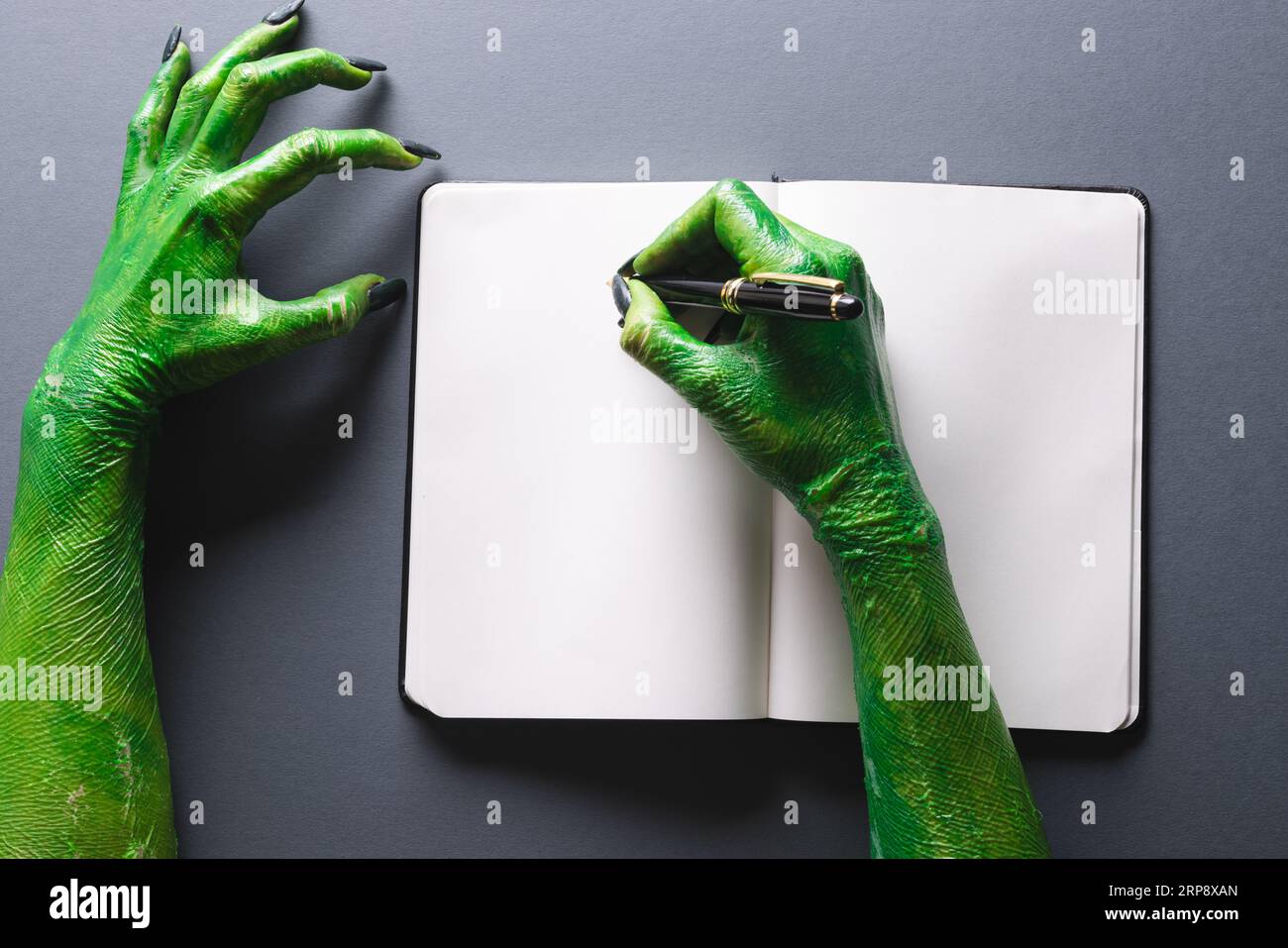 Quaderno verde con le mani mostro e spazio per la copia su sfondo grigio Foto Stock