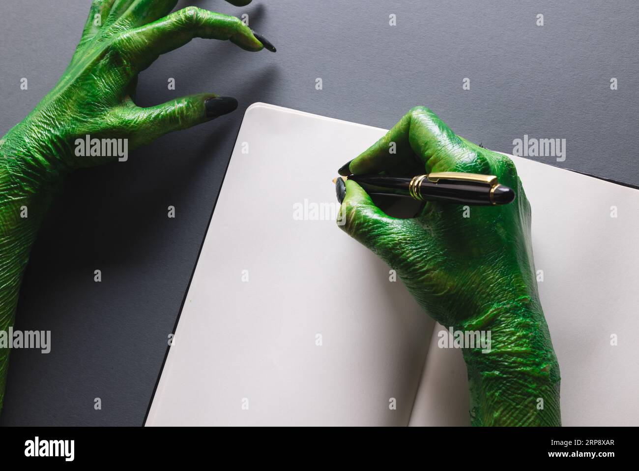 Quaderno verde con le mani mostro e spazio per la copia su sfondo grigio Foto Stock